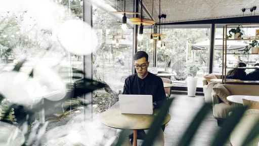 Smart looking young man sitting with a laptop in a cafe.