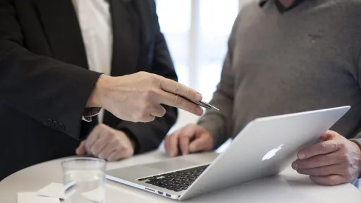 Consultant Drupal en France. Deux personnes discutent autour d'un ordinateur sur une table.
