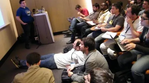 Conférence en salle, participants assis et attentifs.